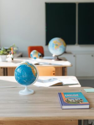 Classroom interior featuring globes, English book, and desks in sunlight