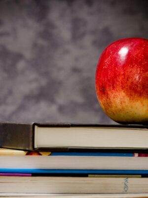 Red apple placed atop stacked books symbolizes education and learning.