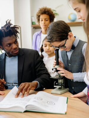 Students and teacher in a science class using a microscope for learning.