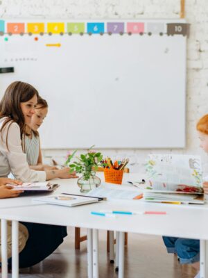 Students and teacher interacting in a bright, colorful classroom setting.